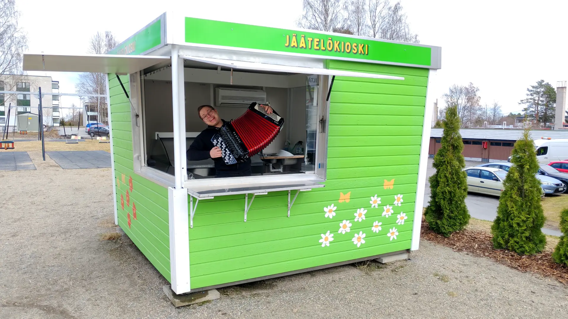 kuvassa vihreä jäätelökioski, jonka sisällö on miesoletettu soittamassa haitaria.